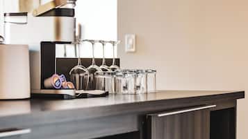 Una cocina moderna con cafetera espresso integrada, copas de vino y microondas.