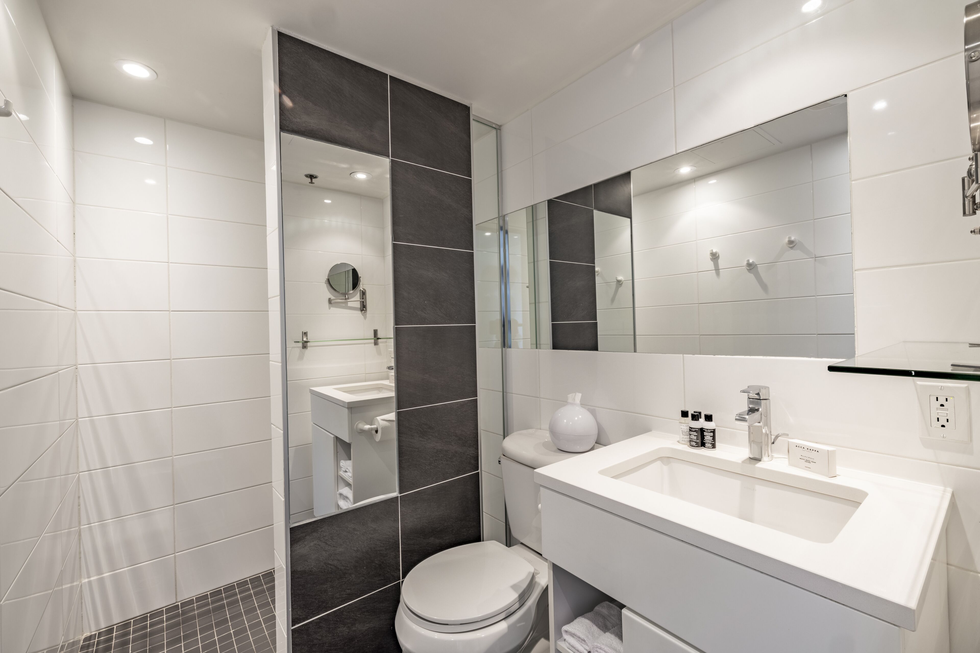 A modern bathroom with a shower, toilet, and sink.