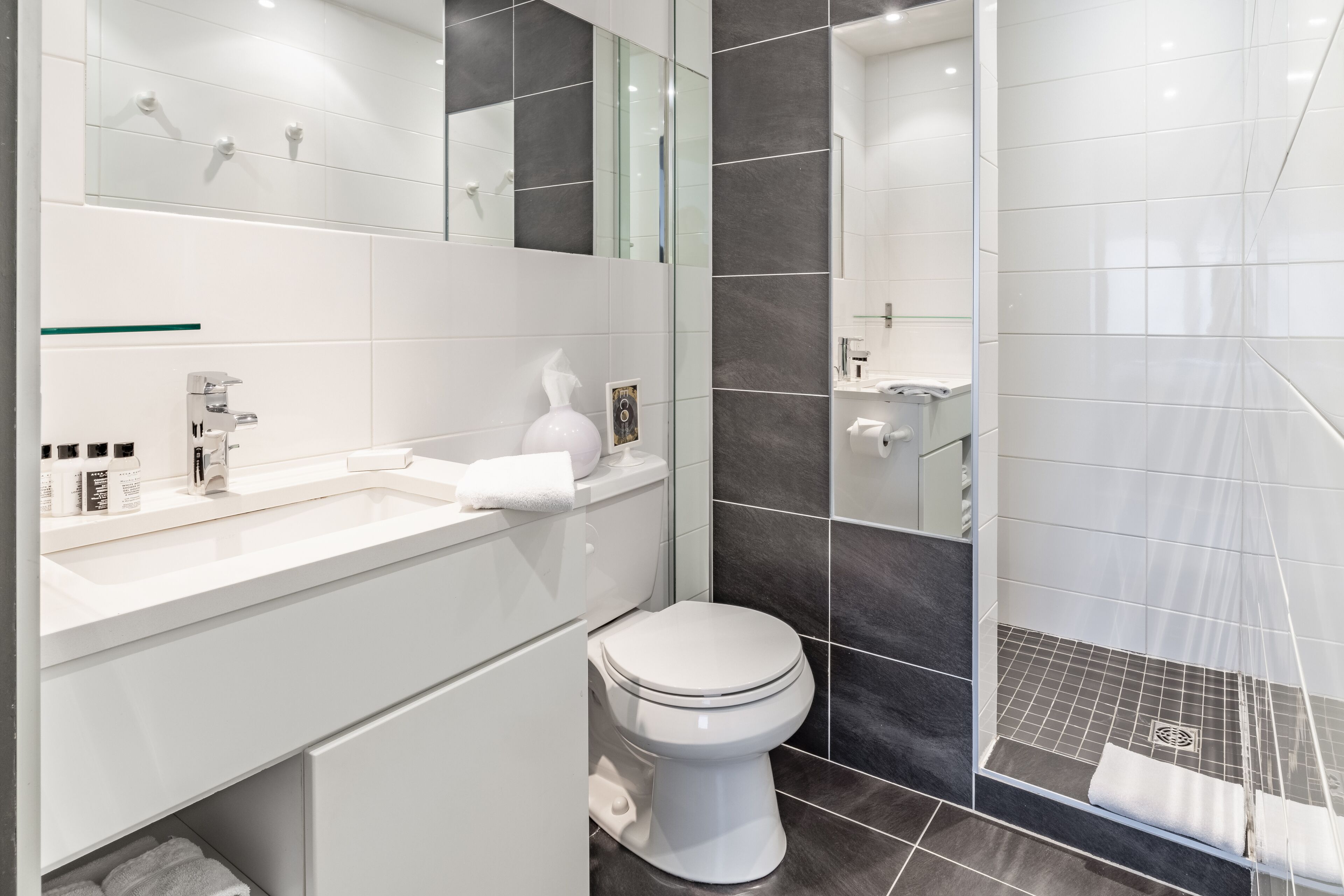 Un baño moderno con un lavamanos blanco, un inodoro y una zona de ducha.