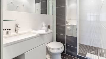 Une salle de bain moderne avec un lavabo blanc, des toilettes et un espace douche.