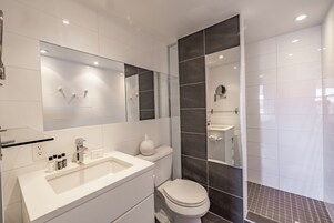 Moderni kylpyhuone, jossa on valkoinen pesuallas, wc ja suihkutila.