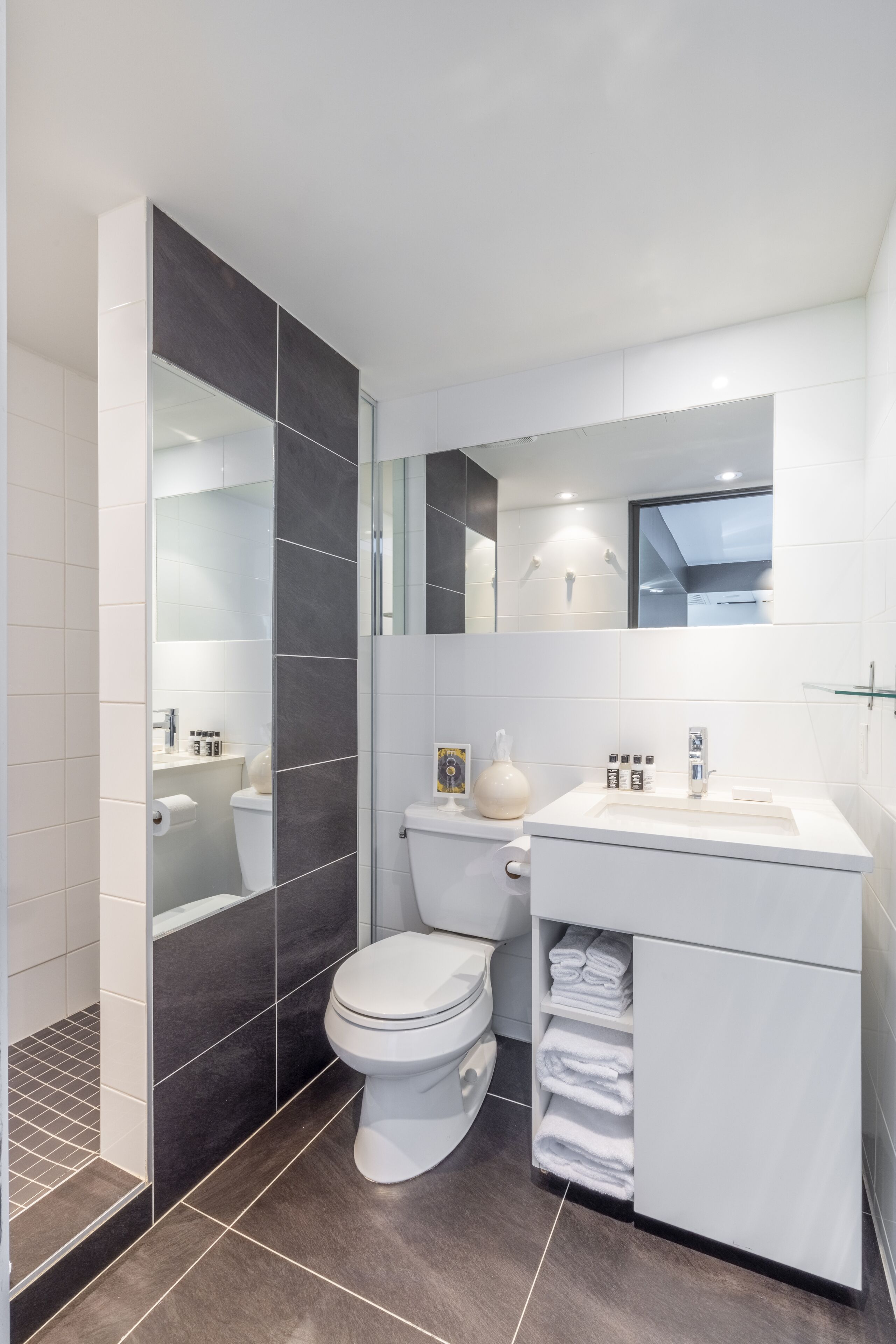 Een moderne badkamer met een wit toilet, een douchecabine van glas en een wastafel met spiegel.