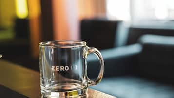 Une tasse en verre transparent portant l’inscription « ZERO | 1 » et posée sur une surface en bois.