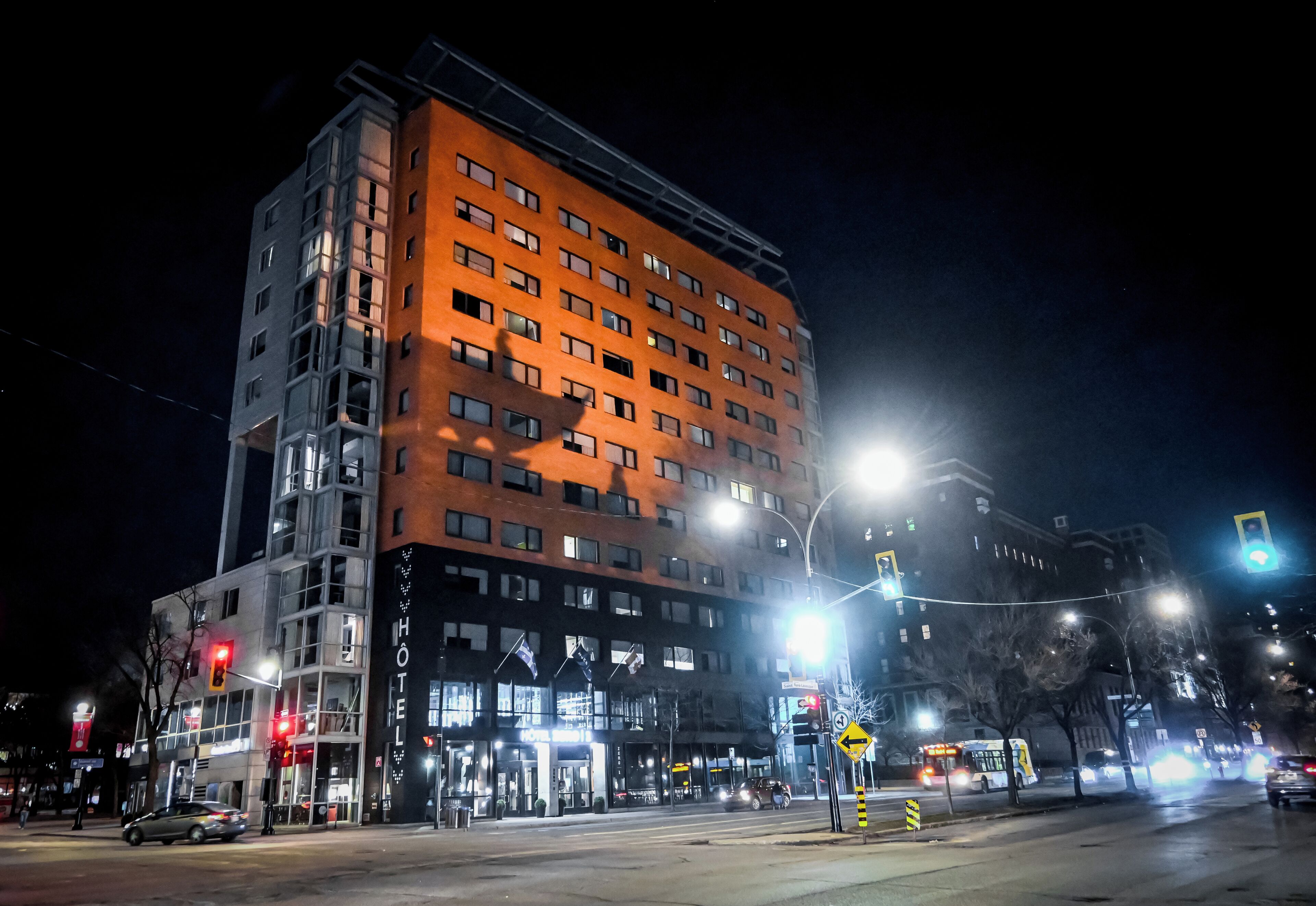 A multi-story hotel with a prominent orange facade, illuminated windows, and a visible entrance with signage.