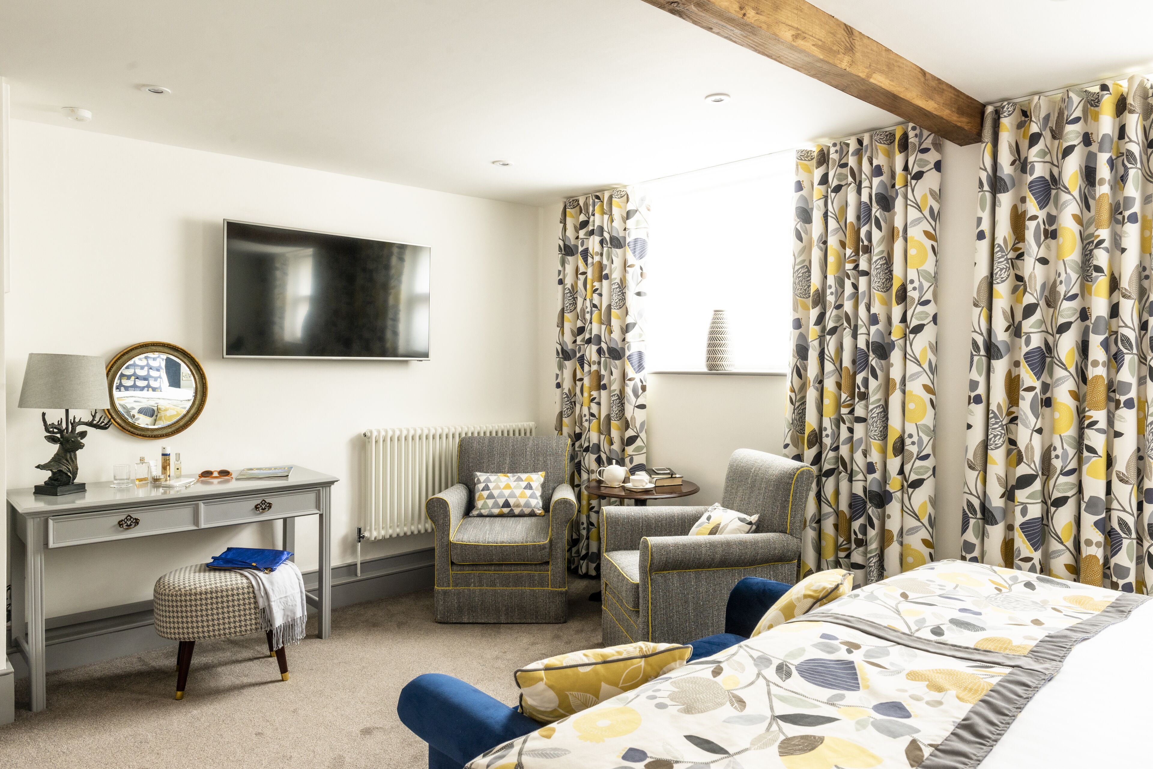 Une chambre d’hôtel comprenant un lit, deux fauteuils, un bureau, une télévision et un radiateur.