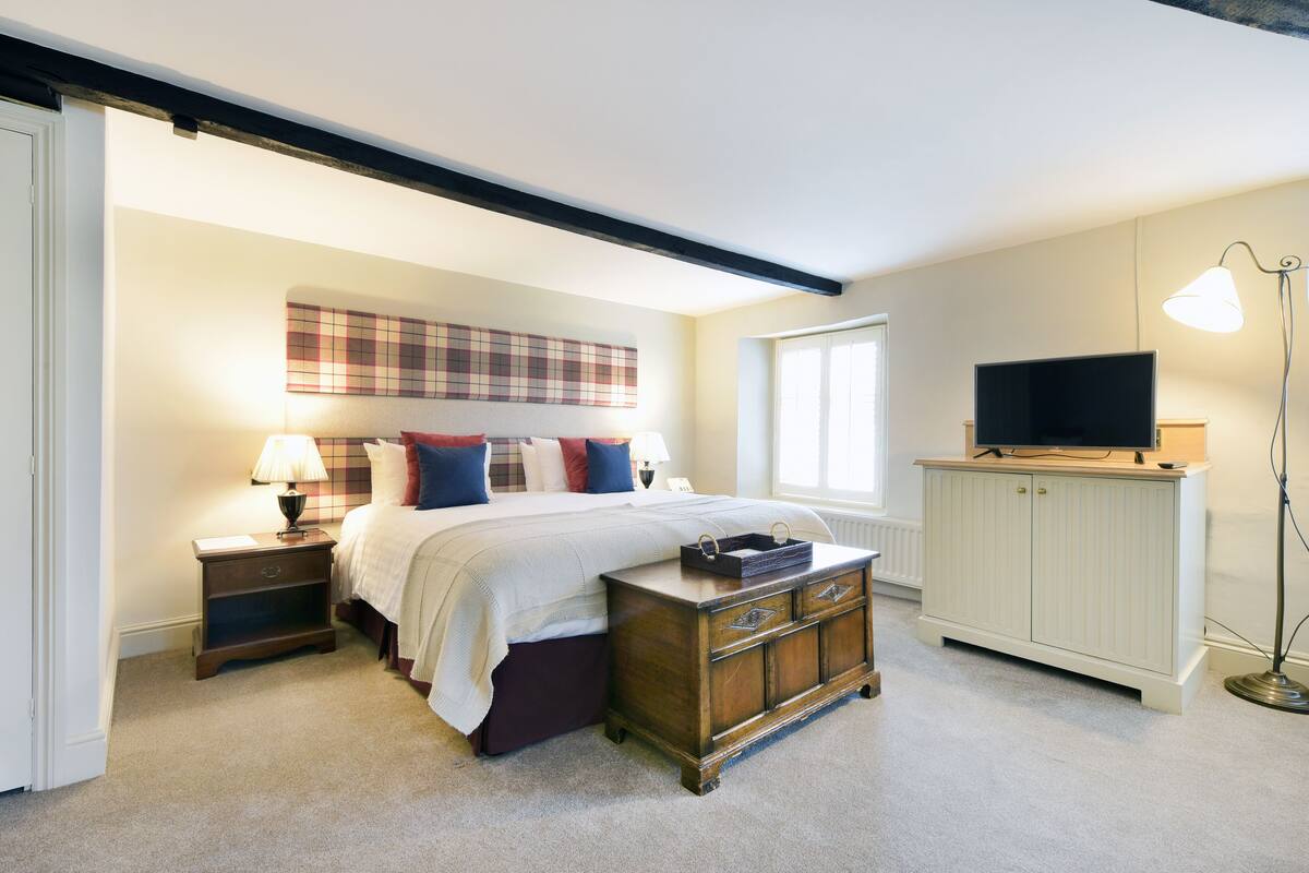 Une chambre à coucher comprenant un lit, des tables de chevet, une commode, un téléviseur et une lampe.