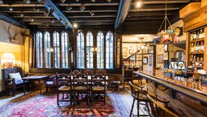 A traditional pub interior with a wooden bar, high windows, and a patterned carpet. - Luttrell Arms Hotel (Minehead)