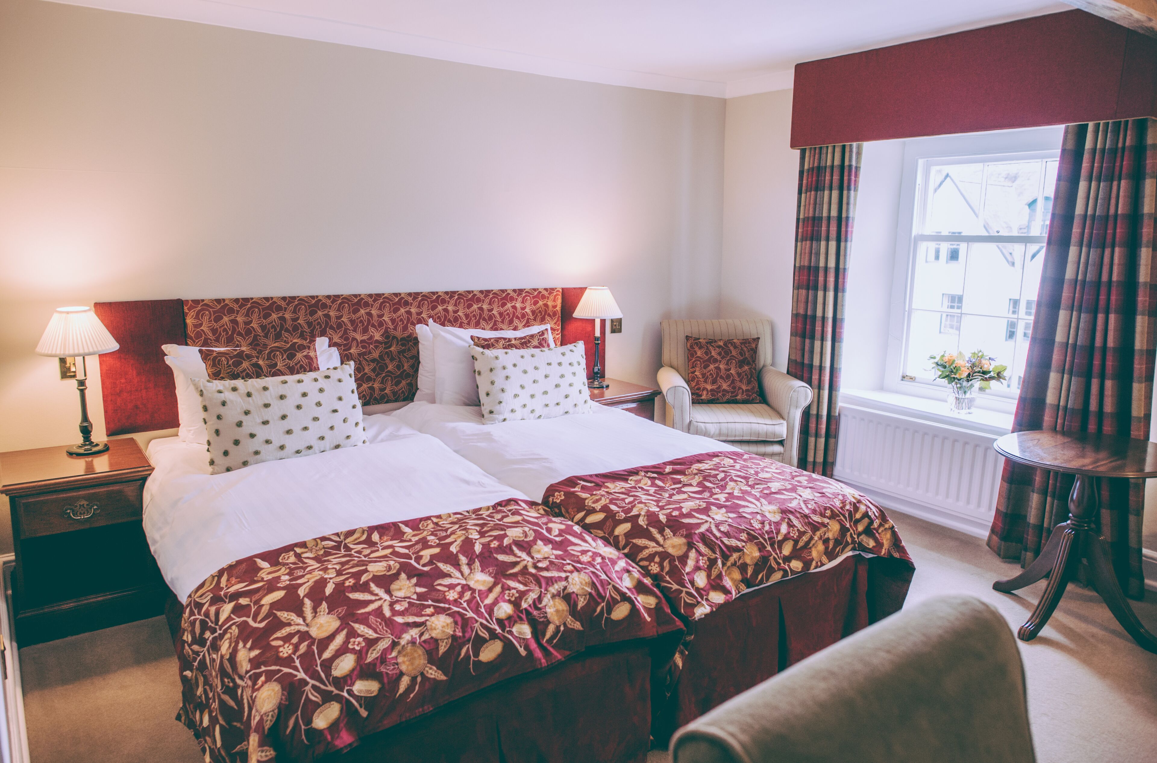 A hotel room with a large bed, two bedside tables, a chair, and a window with curtains.