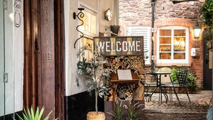 A rustic interior with a 'WELCOME' sign, wooden door, stone walls, and a patterned rug. - Luttrell Arms Hotel (Minehead)