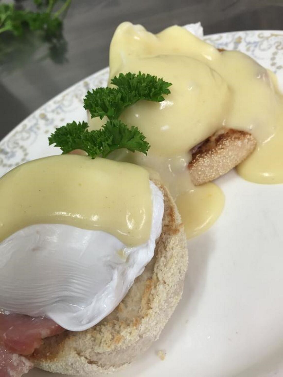 A plate with eggs benedict, including poached eggs and hollandaise sauce, garnished with parsley.