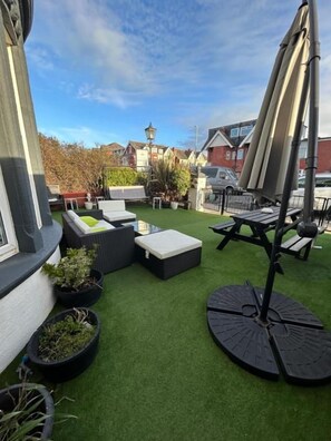 A patio with artificial grass, outdoor furniture, and a pergola with umbrellas. - North Crest (Blackpool)