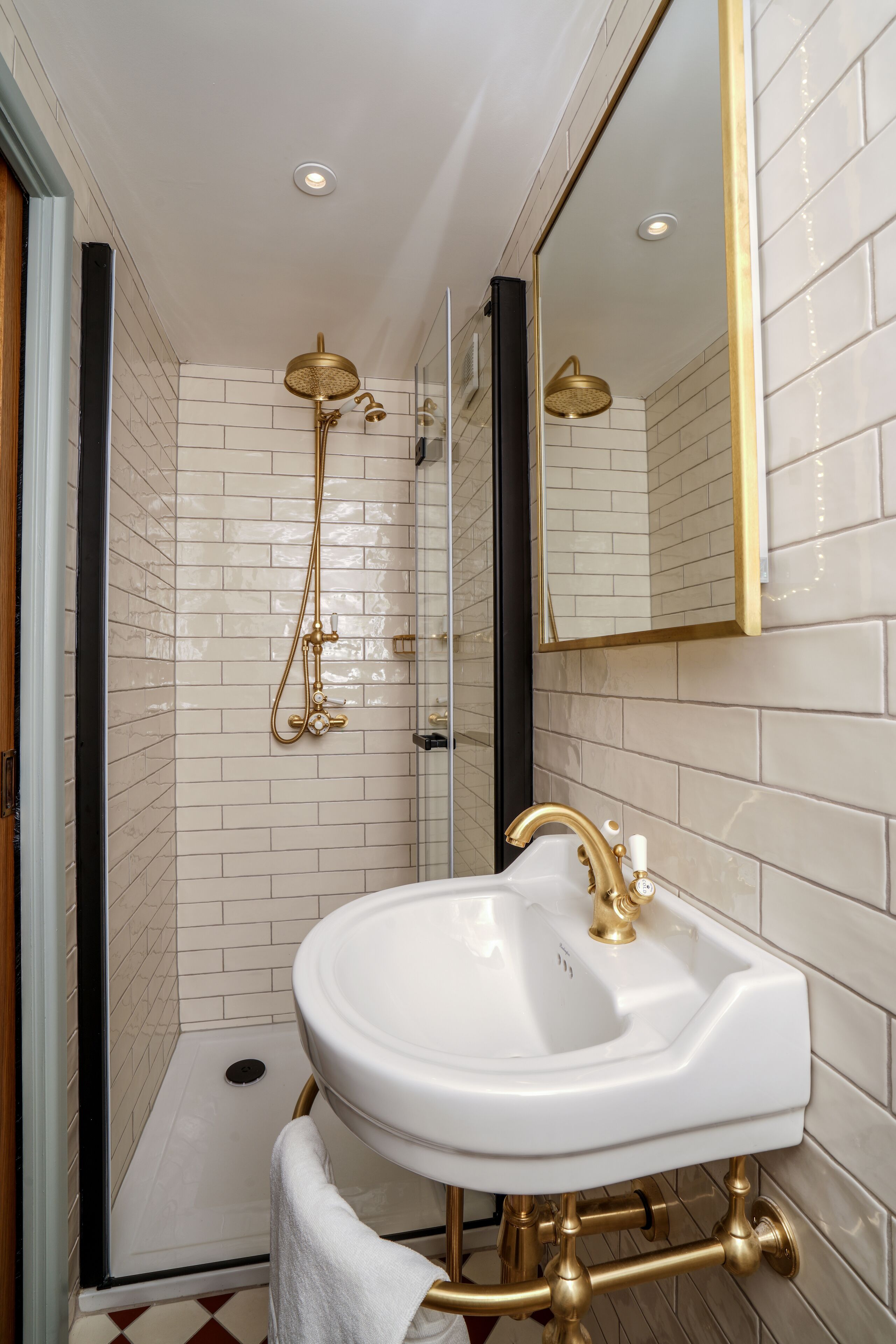 A bathroom with a white sink, gold fixtures, and a shower with a gold showerhead.