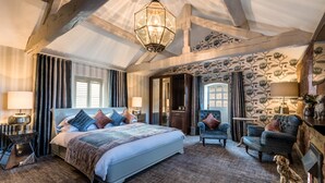 Une chambre spacieuse avec un grand lit, des poutres apparentes, un lustre et un mur décoratif.