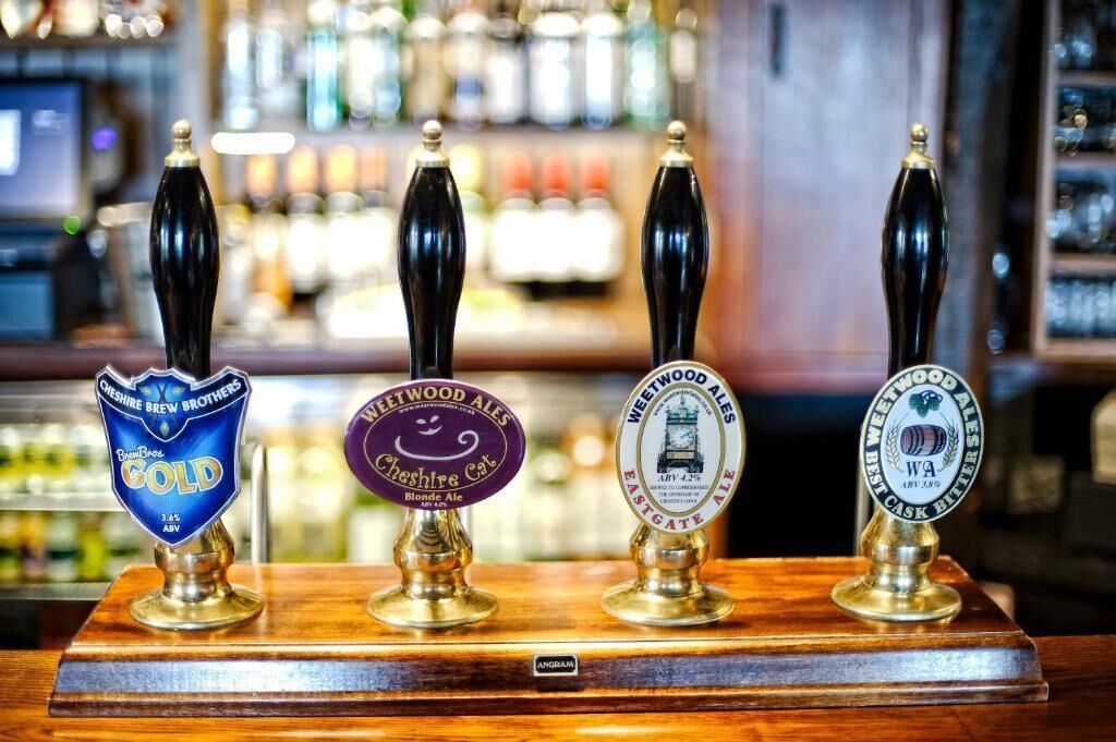 Un bar doté de quatre tireuses à bière, chacune affichant une marque et un type de bière différents.
