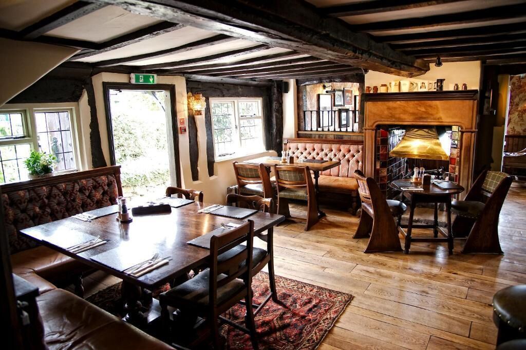 A traditional inn with exposed wooden beams, a fireplace, and a cozy seating area.