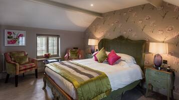 Un dormitorio con una cama grande, dos sillas, una mesita de noche y una ventana con persianas.