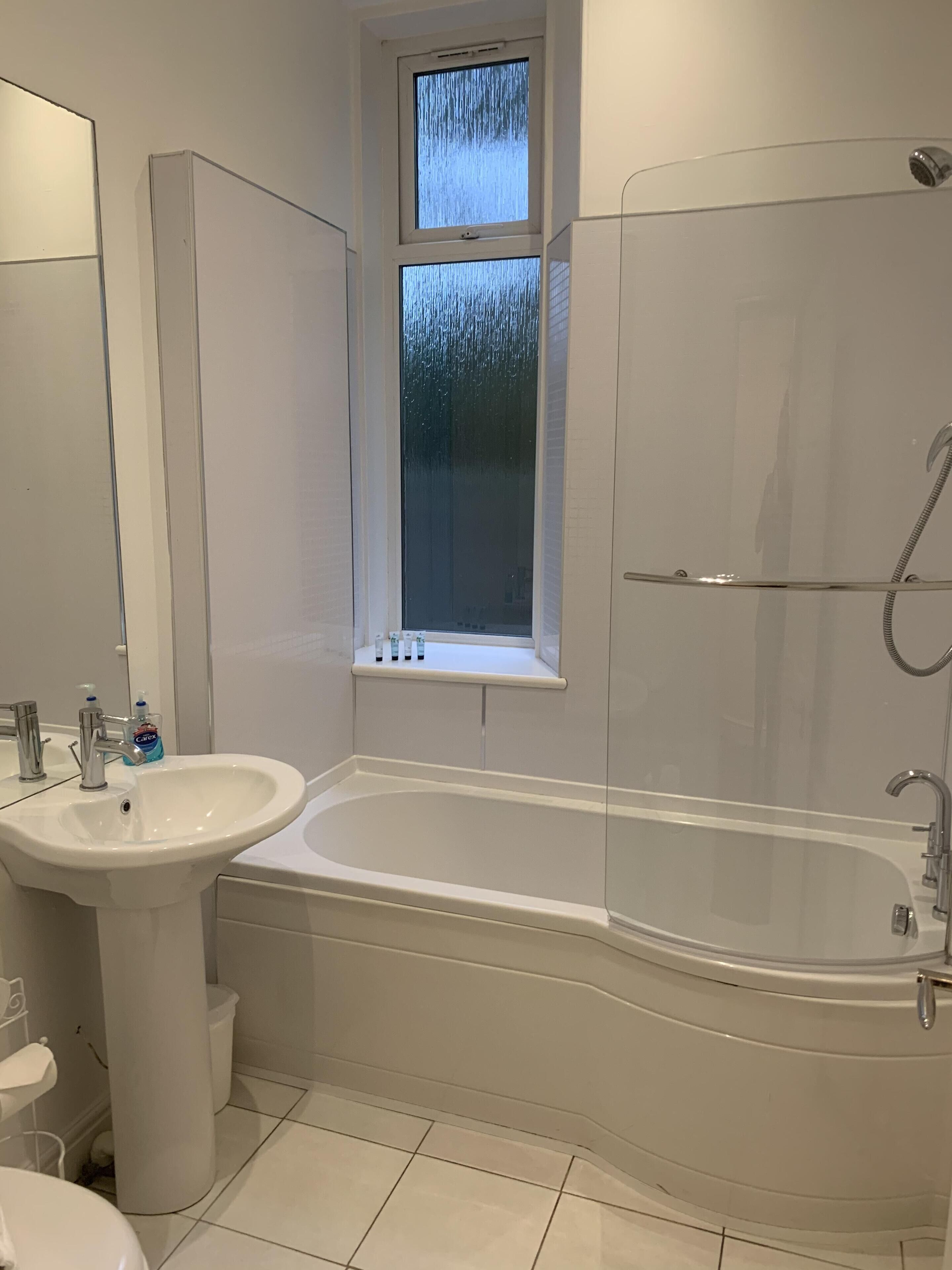 Une salle de bain avec un lavabo blanc, une baignoire et une douche.