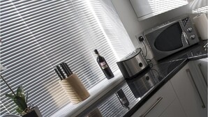 Una cocina moderna con ventana, microondas, hervidor y una botella de vino.