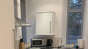 Una cocina compacta equipada con microondas, estufa, horno y lavadora integrada.