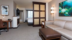 A hotel room with a bed, a sofa, a desk, a chair, a TV, and a painting on the wall. - Hyatt Place Sarasota/Bradenton Airport (Sarasota)