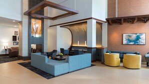 A modern lobby with a sectional sofa, a curved seating area, and a brick accent wall. - Hyatt Place Sarasota/Bradenton Airport (Sarasota)