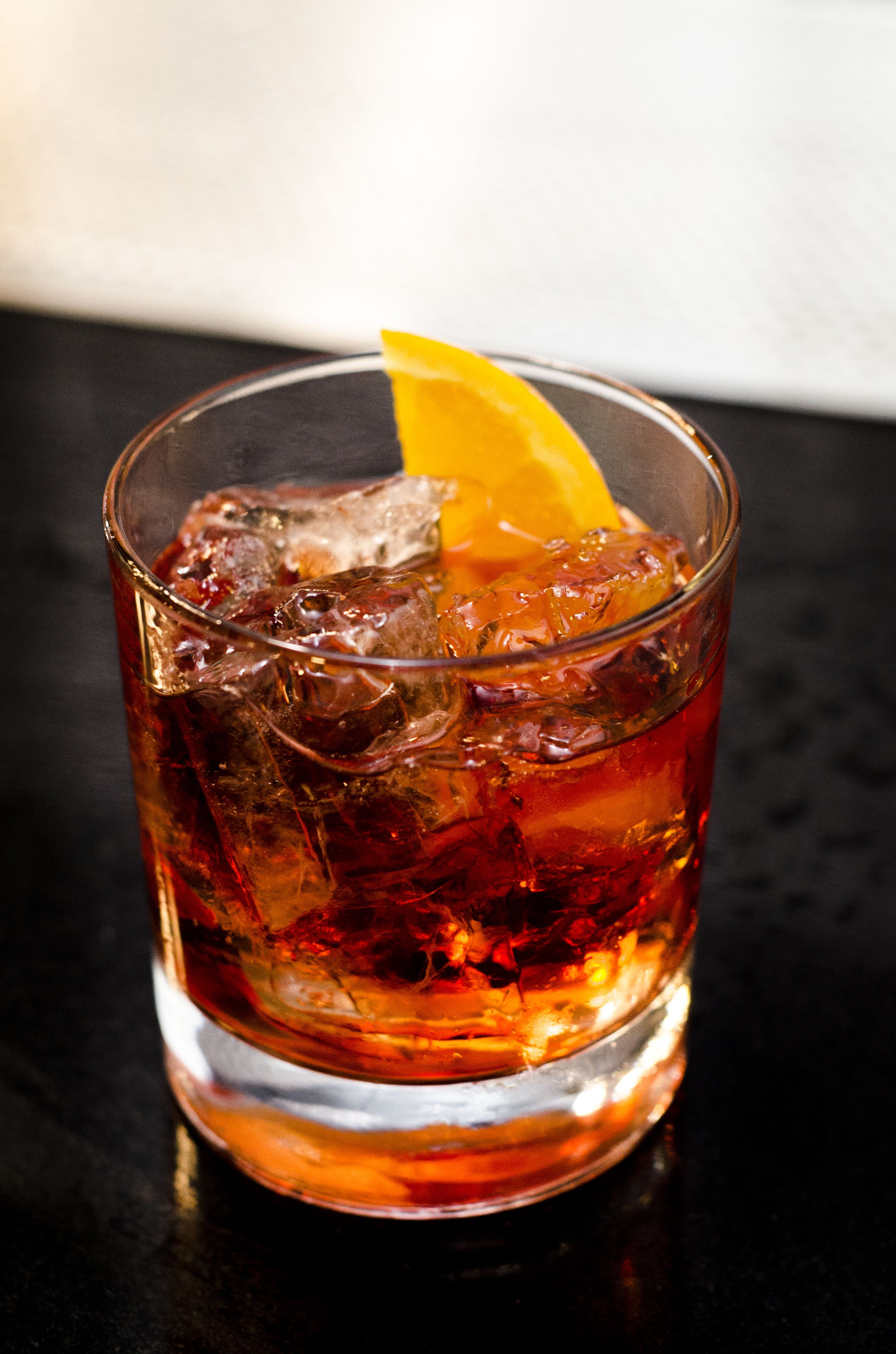 Un verre d’une boisson ambrée, avec des glaçons et une tranche d’orange.