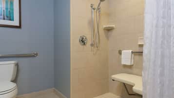 A bathroom with a toilet, a shower with a handheld showerhead, and a grab bar.
