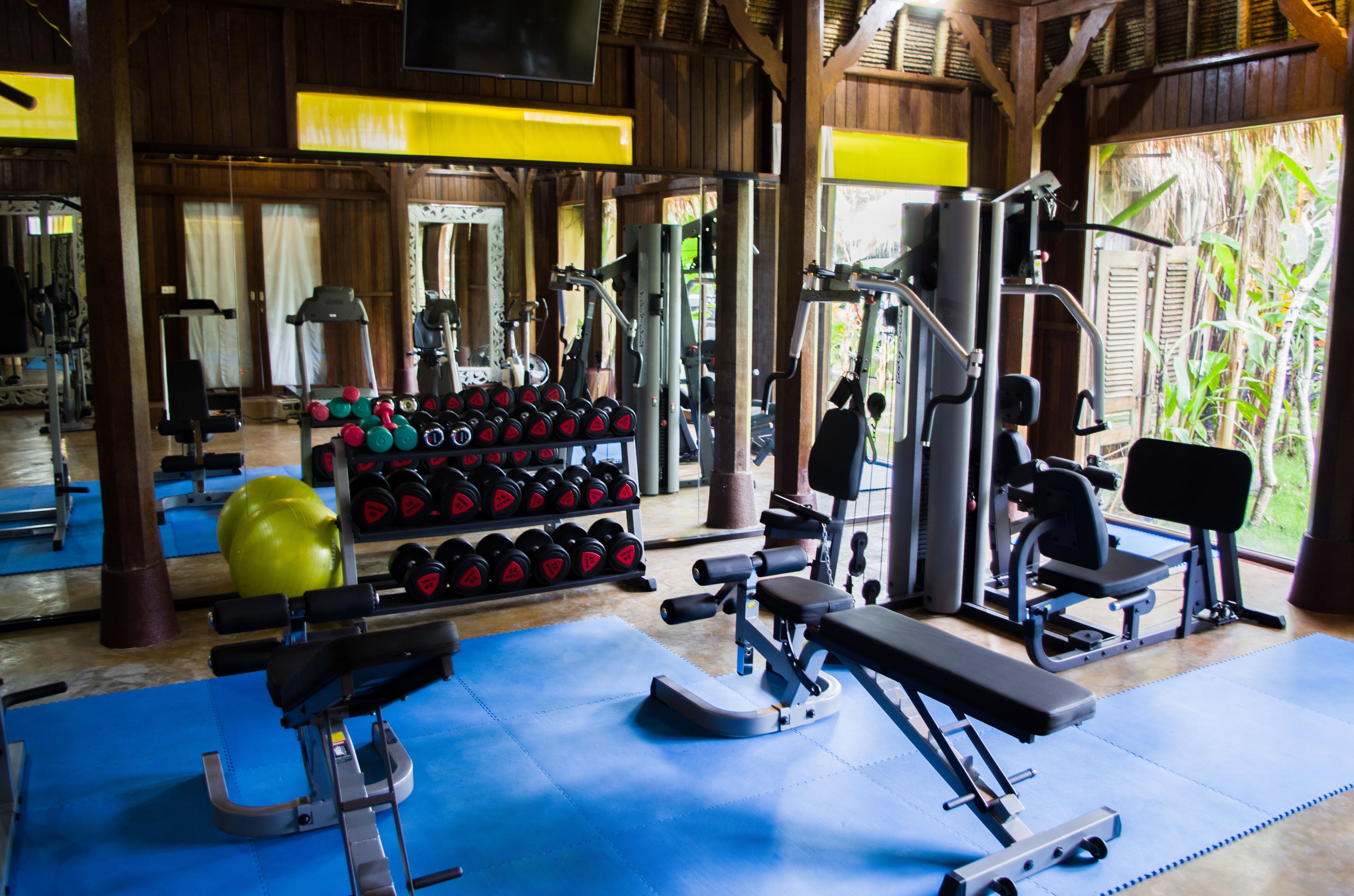 Ett gym med träningsredskap, vikter och ett blått golv.