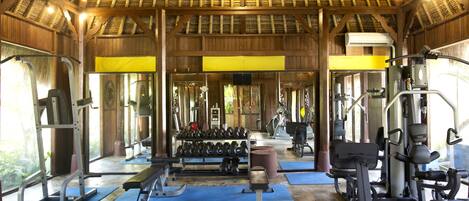 Un gimnasio con equipo de ejercicio, bancos y mancuernas.