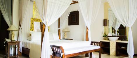 A four-poster bed with white drapes, a wooden bench, a bedside table with a lamp, and a mirror above the sink.