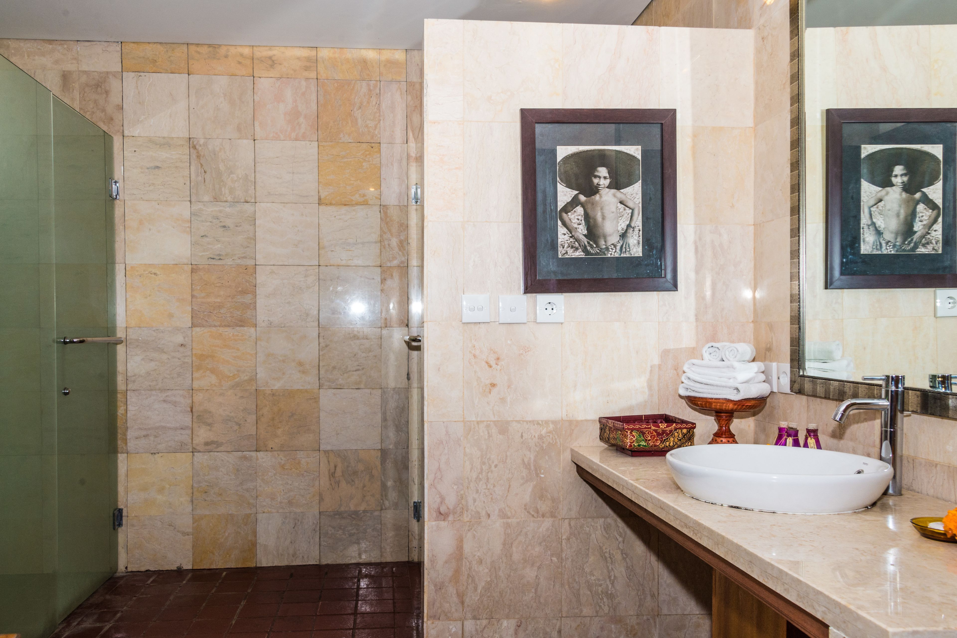 A bathroom with a large sink, a mirror, and two framed pictures on the wall.