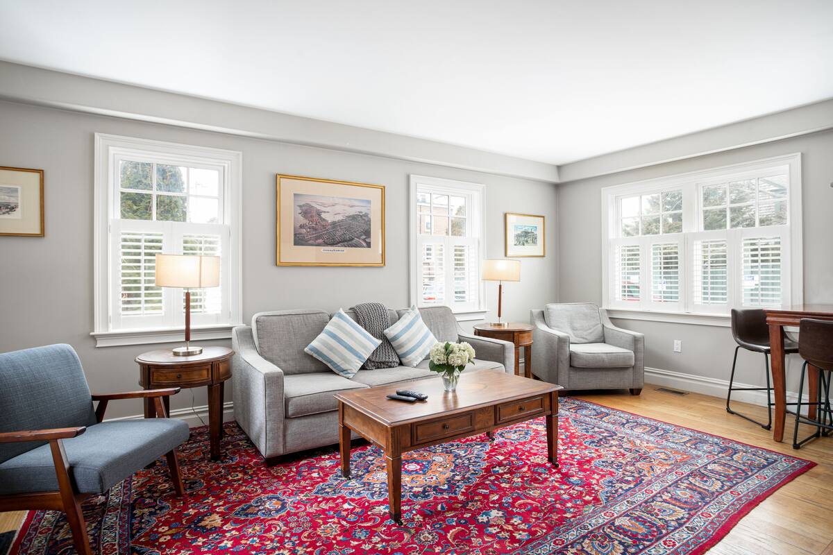 A living room with a grey sofa, a wooden coffee table, and a red patterned rug.