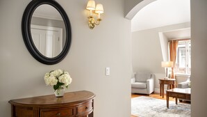 Una habitación con una consola de madera, un espejo y apliques en la pared.