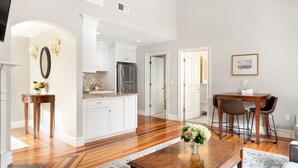 Una cocina amplia con armarios blancos, un refrigerador de acero inoxidable y un comedor con mesa y sillas de madera.