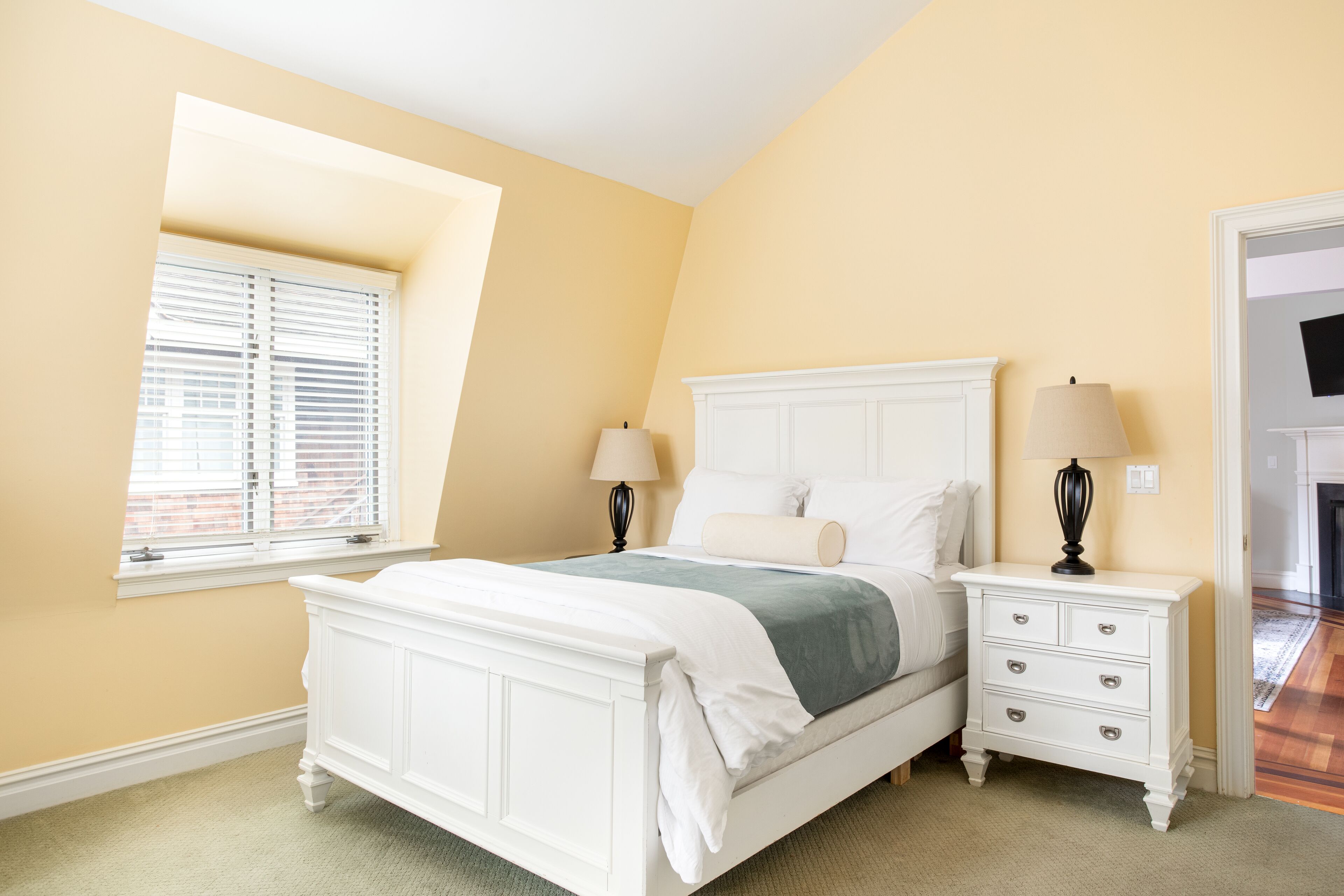 A bedroom with a bed, bedside tables, and a window.