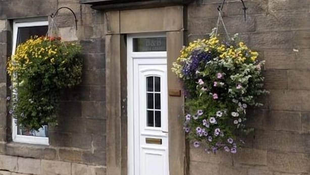 Un edificio con una puerta blanca y dos macetas colgantes de flores.