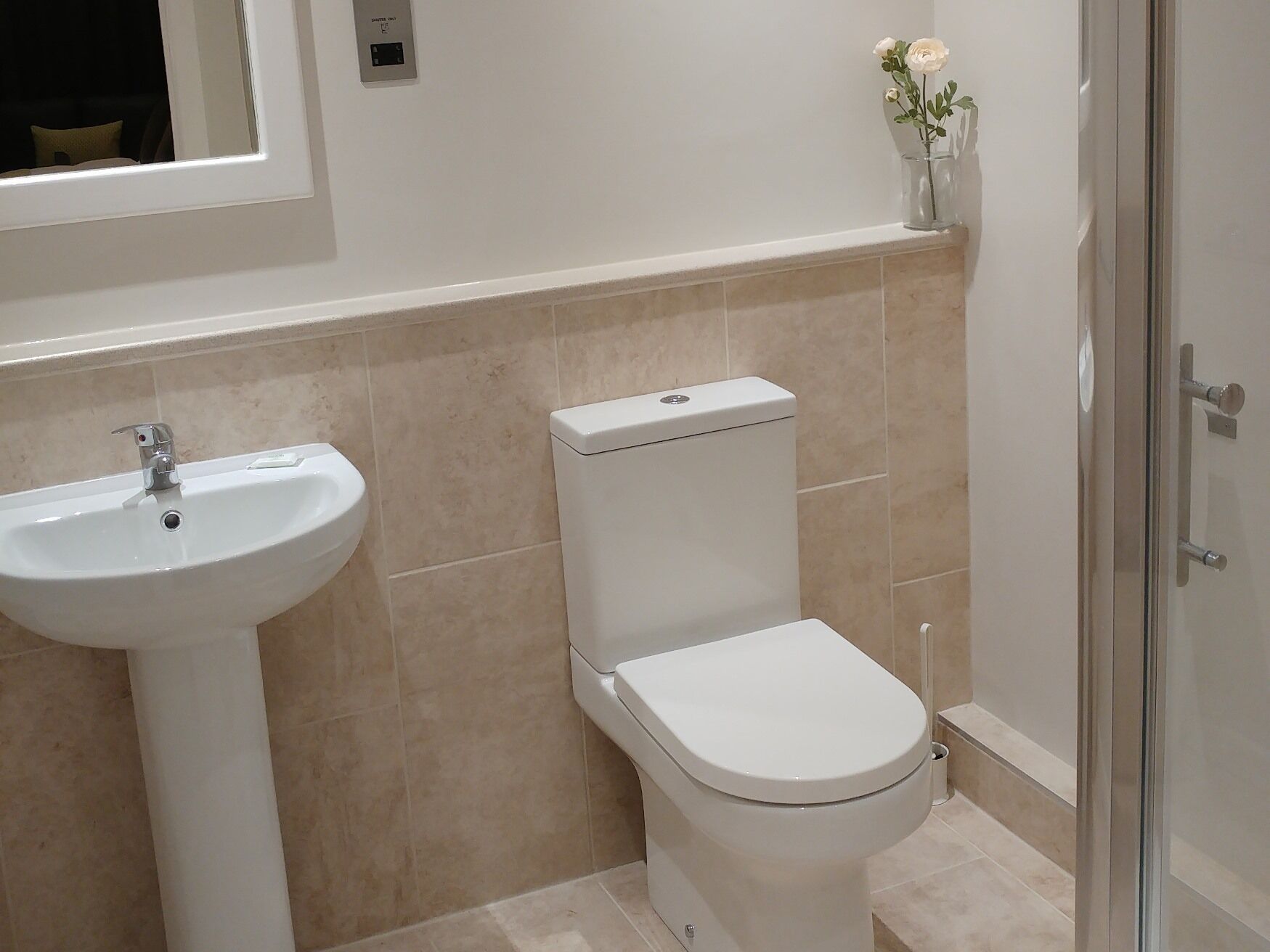 Ein Badezimmer mit einem weißen Waschbecken, einer Toilette und einer Duschkabine aus Glas.