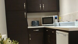 A compact kitchen with dark cabinets, a microwave, a coffee maker, and a dishwasher. - Swan Studios (Choppington)