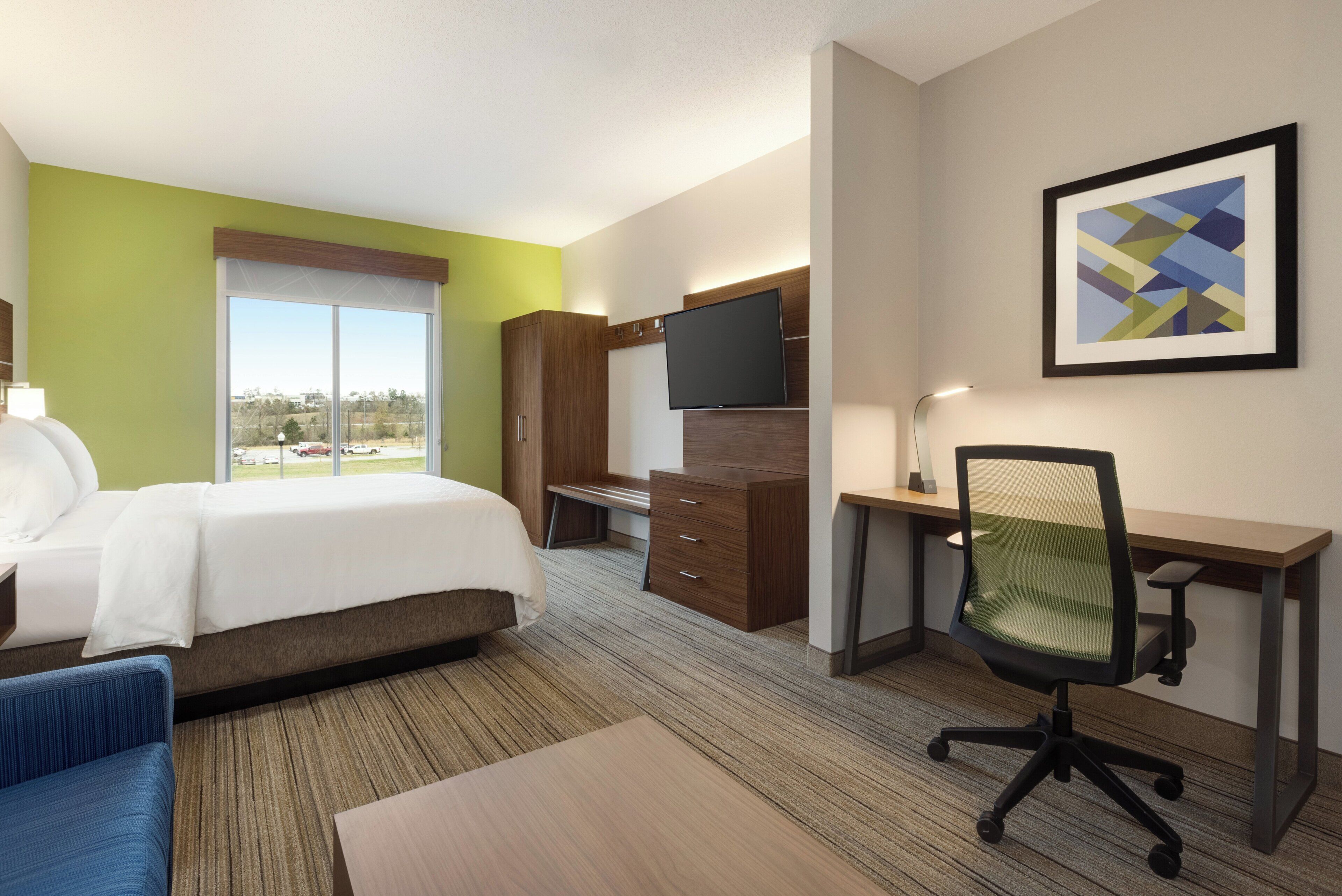 Habitación de hotel con cama, escritorio, silla y televisor.