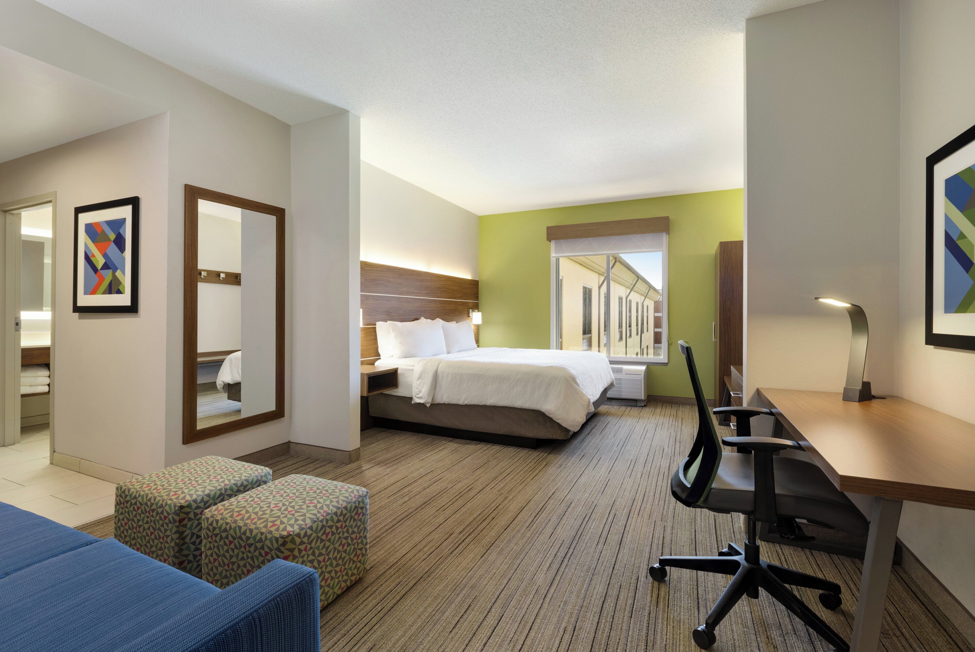 A hotel room with a bed, a desk, a chair, and a small couch.