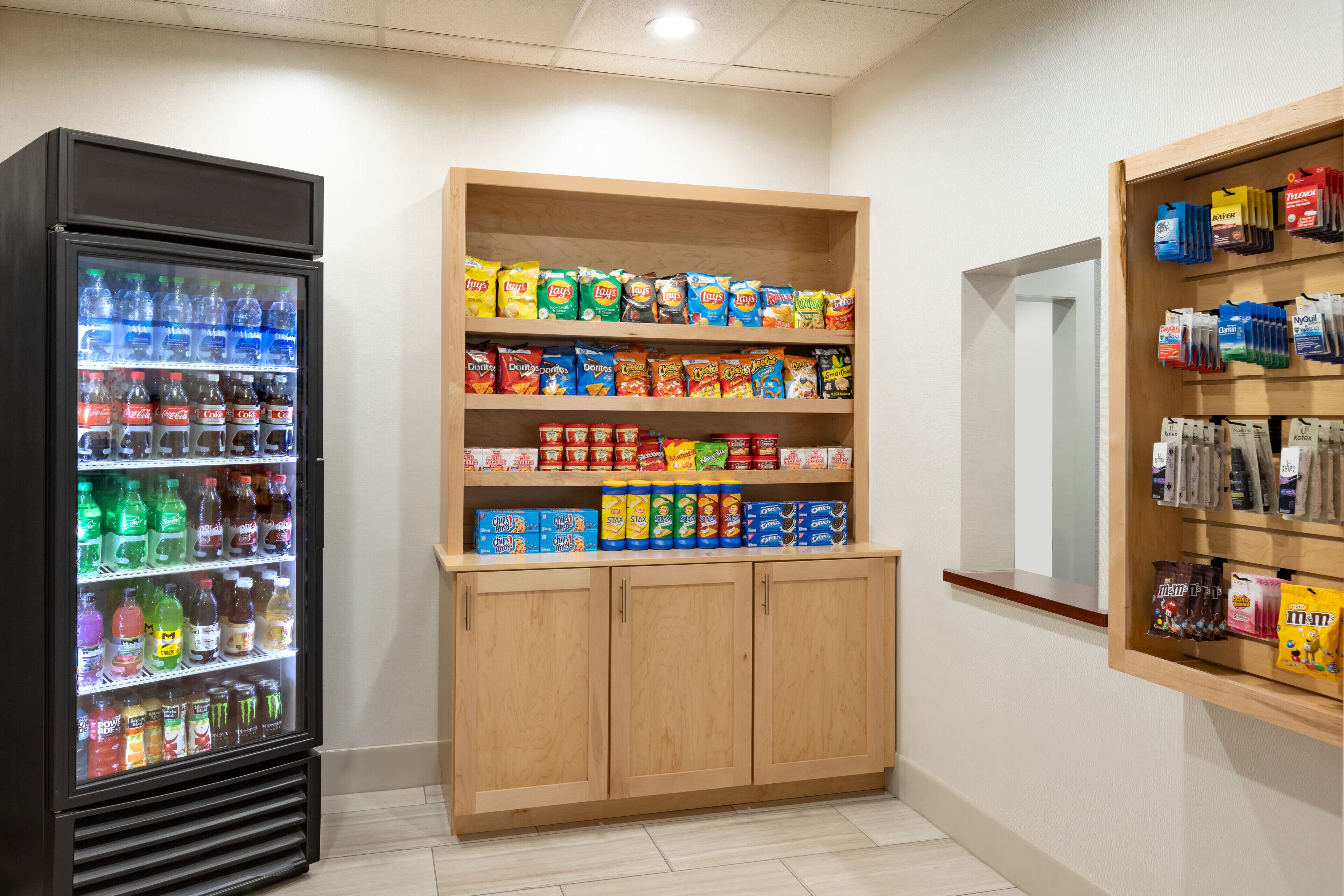 A vending machine with various drinks and snacks, a shelf with packaged snacks, and a display of coffee pods.