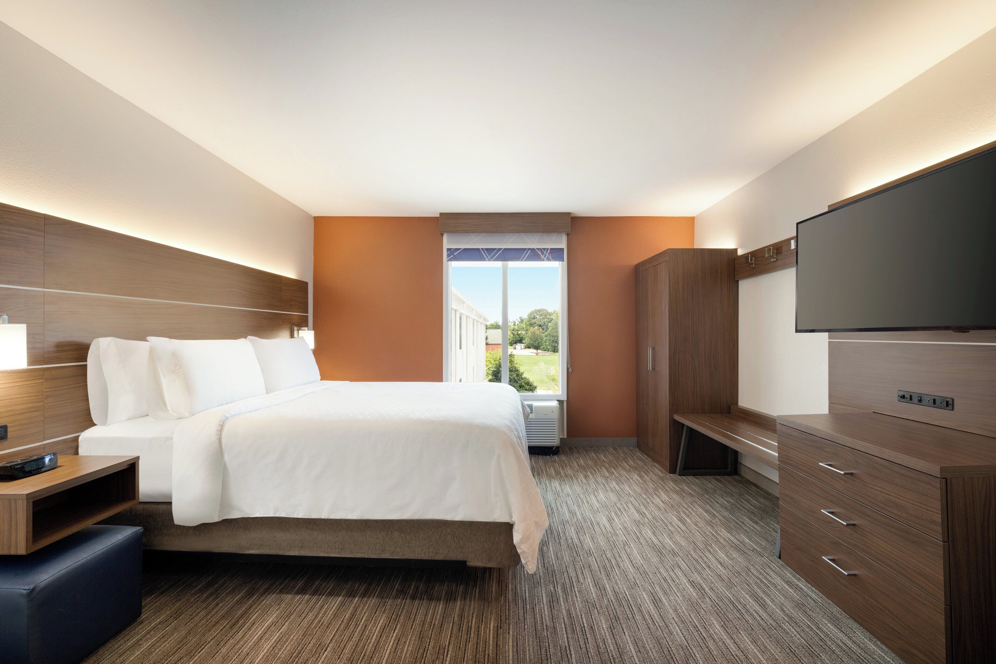 Une chambre d’hôtel équipée d’un lit, d’une télévision, d’un bureau et d’une armoire.