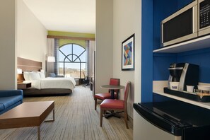 Una habitación de hotel con cama, escritorio, silla, máquina de café y microondas.