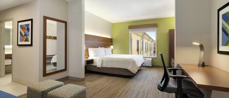 A hotel room with a bed, a desk, a chair, a sofa, and a large window.