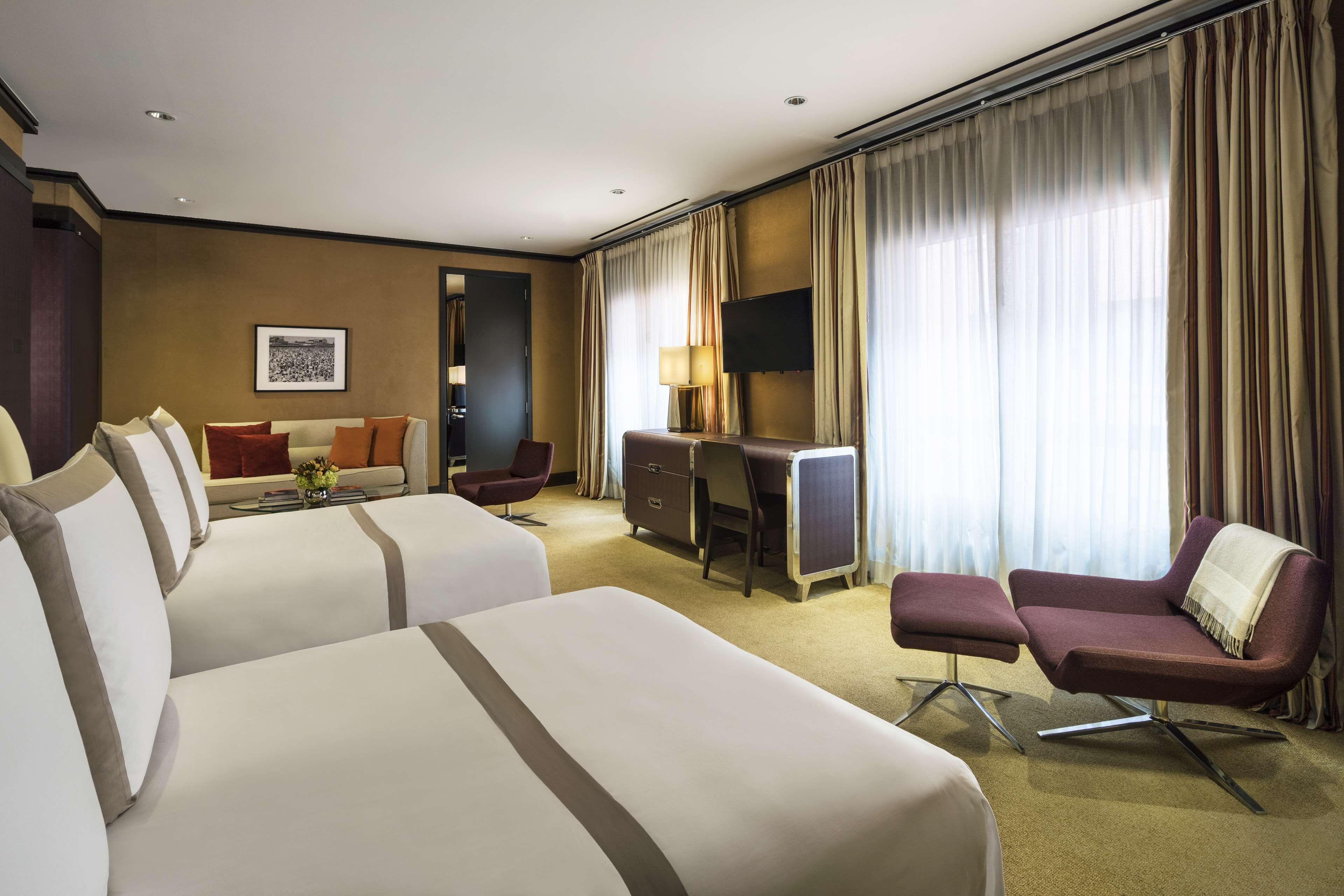 Habitación de hotel con dos camas, un escritorio, una silla y un televisor.
