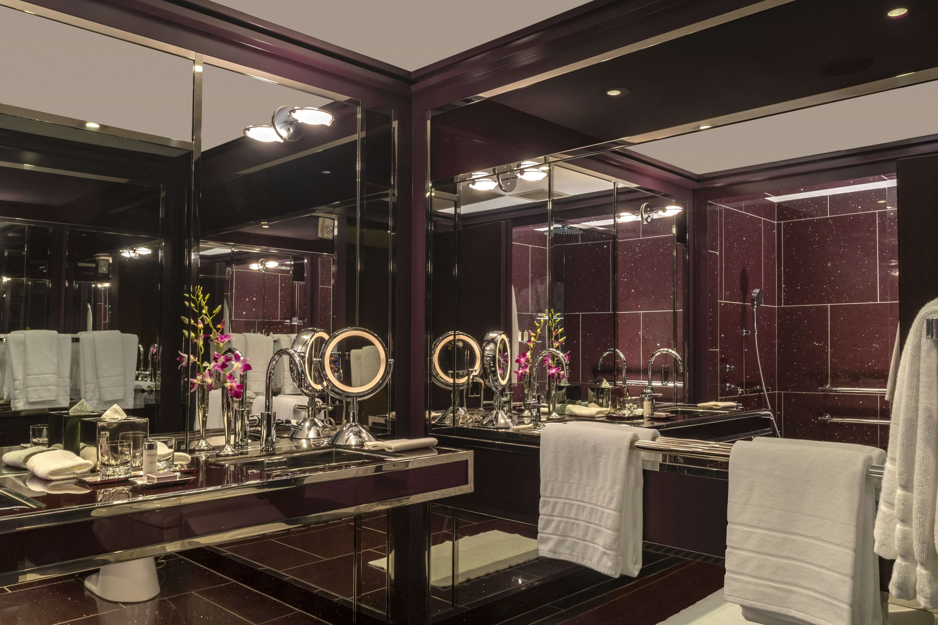 A luxurious bathroom with a large mirror, multiple round mirrors, a vanity with a sink, and a towel rack.