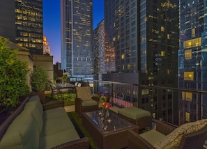 Eine Dachterrasse mit Korbmöbeln, einem Glastisch und einem Blumenstrauß.