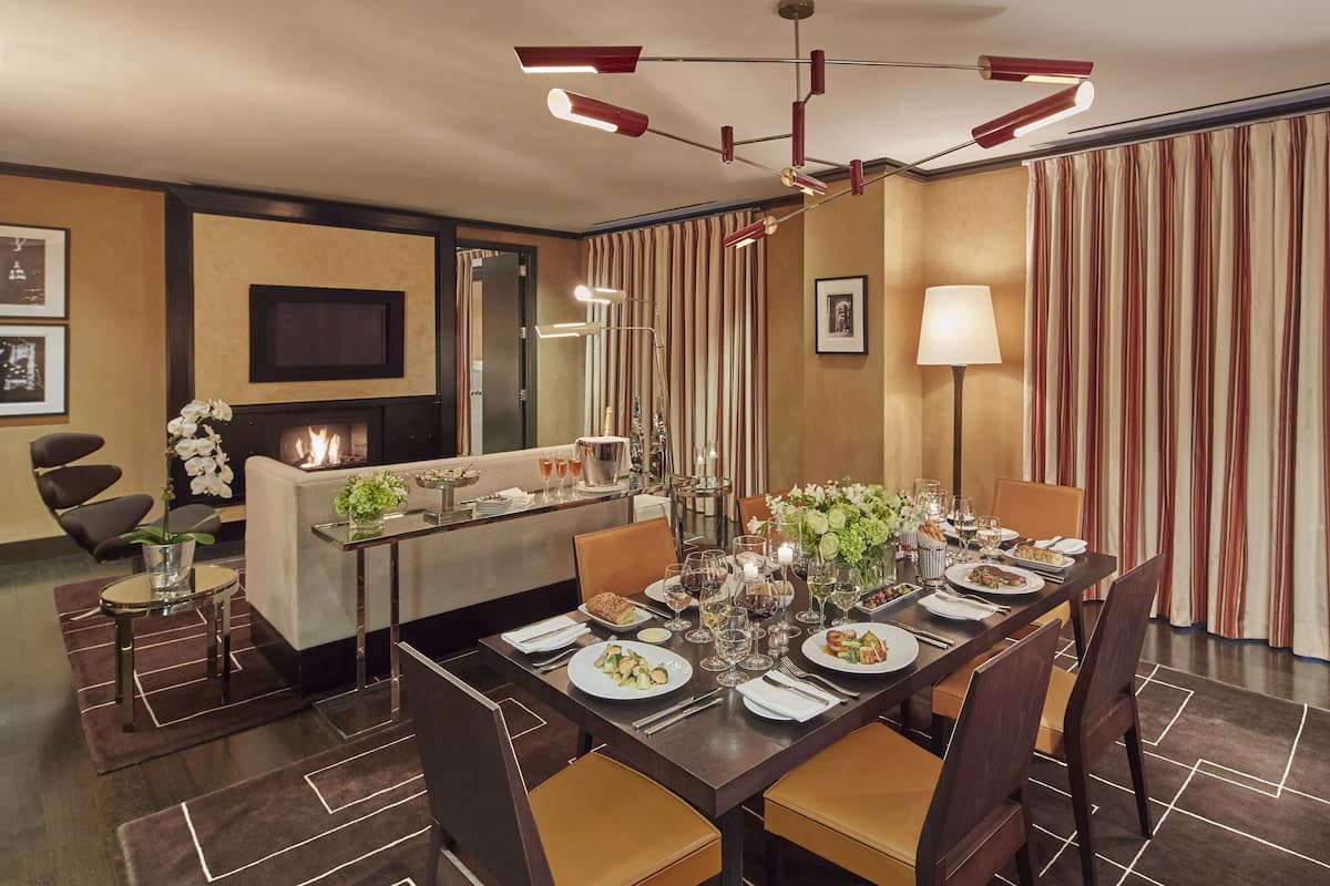 A dining area with a long table set for a meal, a fireplace, and a television on the wall.
