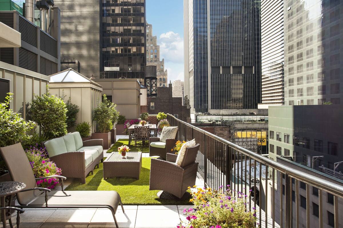 A rooftop patio with outdoor furniture, a small lawn, and city views.