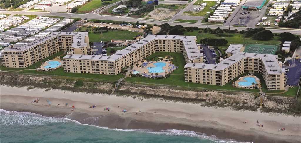 A coastal hotel with multiple buildings, a beach, and a swimming pool.